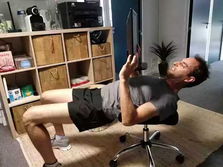 Une personne en tenue de sport qui soulève un écran d’ordinateur.